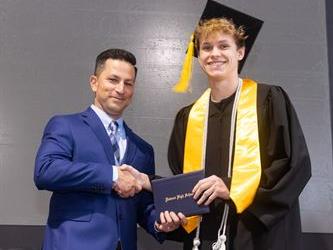 Principal posing with graduating senior