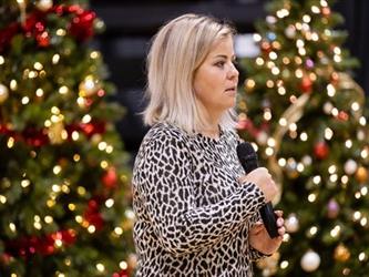 Presenter speaking in front of christmas trees