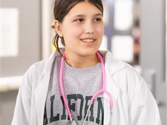 A student is seen wearing a lab coat and stethoscope around her neck