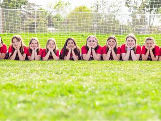 Girls soccer team posing on the ground