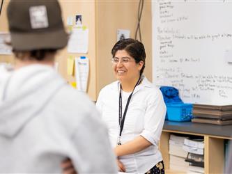 A teacher greets guests with a smile in a classroom