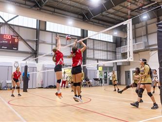 Futures Girls Volleyball team jumping to block