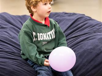 A child is sat on a bean bag with a balloon in hand
