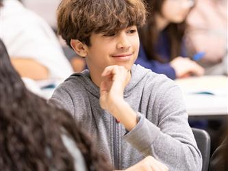 A student is seen smiling at his desk